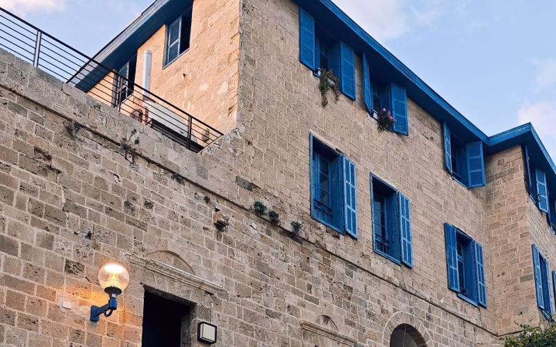 בניין אבן עתיק עם תריסים כחולים ביפו – ג'נטריפיקציה ומחירי הנדל"ן